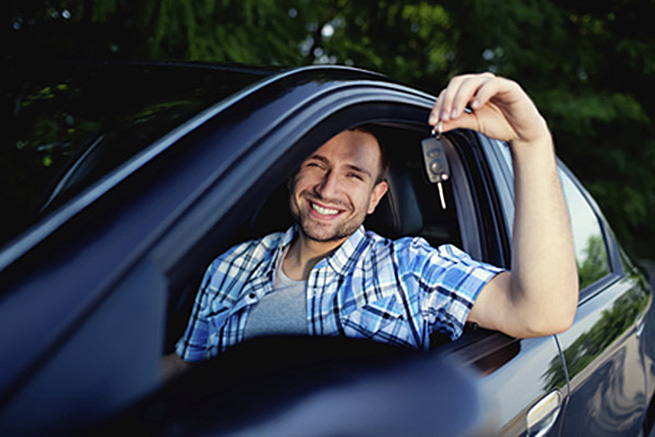 Young man with keys of new car smiling