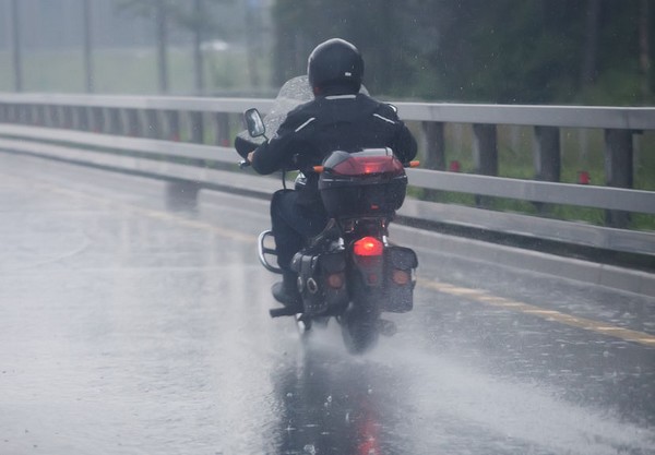 62930155 - motorcyclist moves on motorcycle on highway to rainy weather